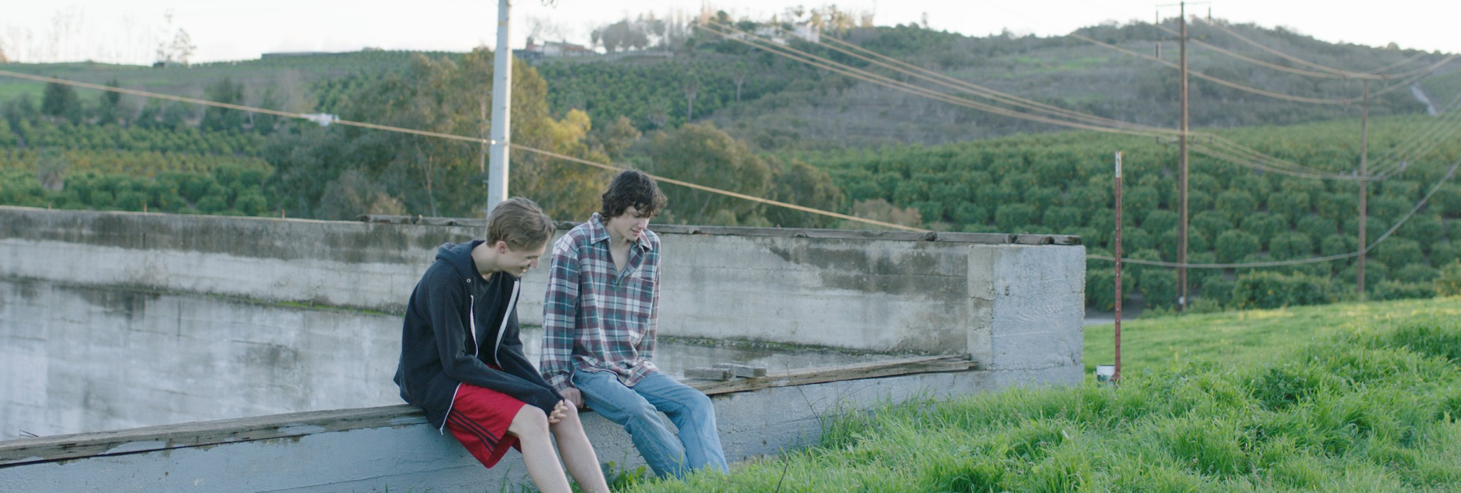 Red scene still: two characters seated outdoors